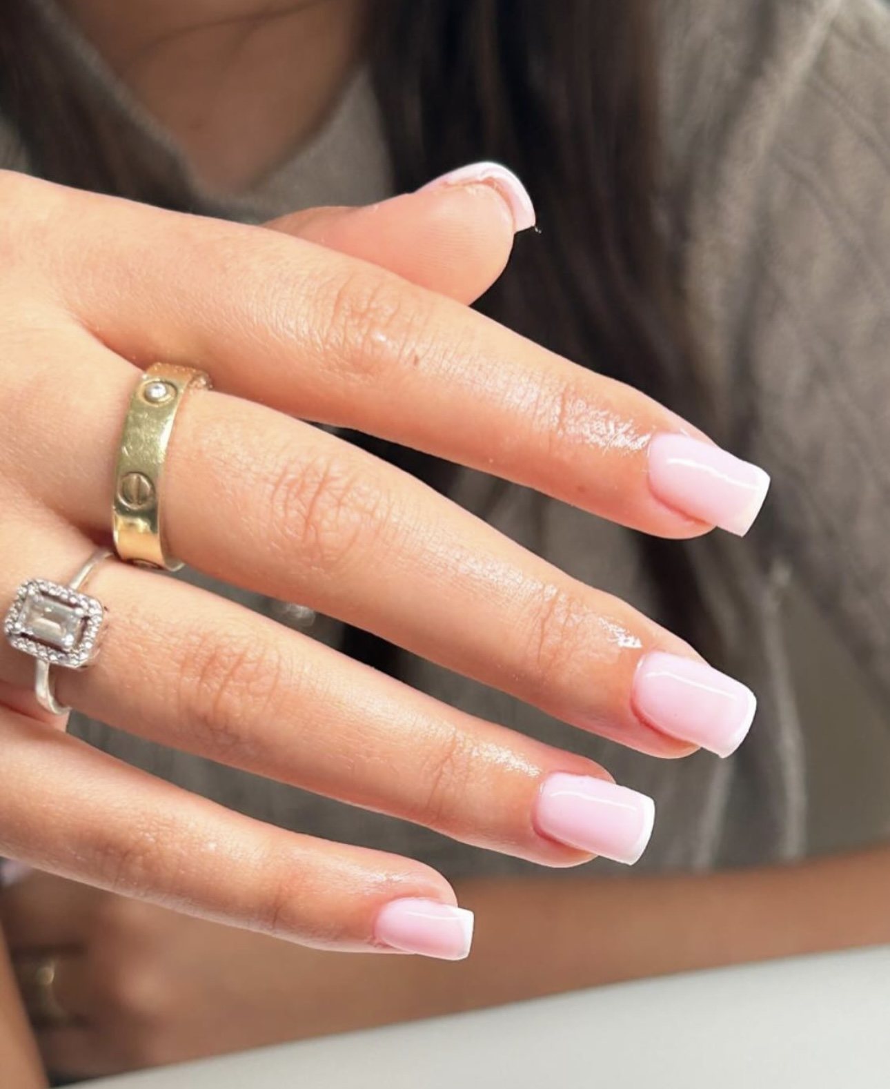 BIAB in zacht roze op vierkante nagels, een hand met ringen